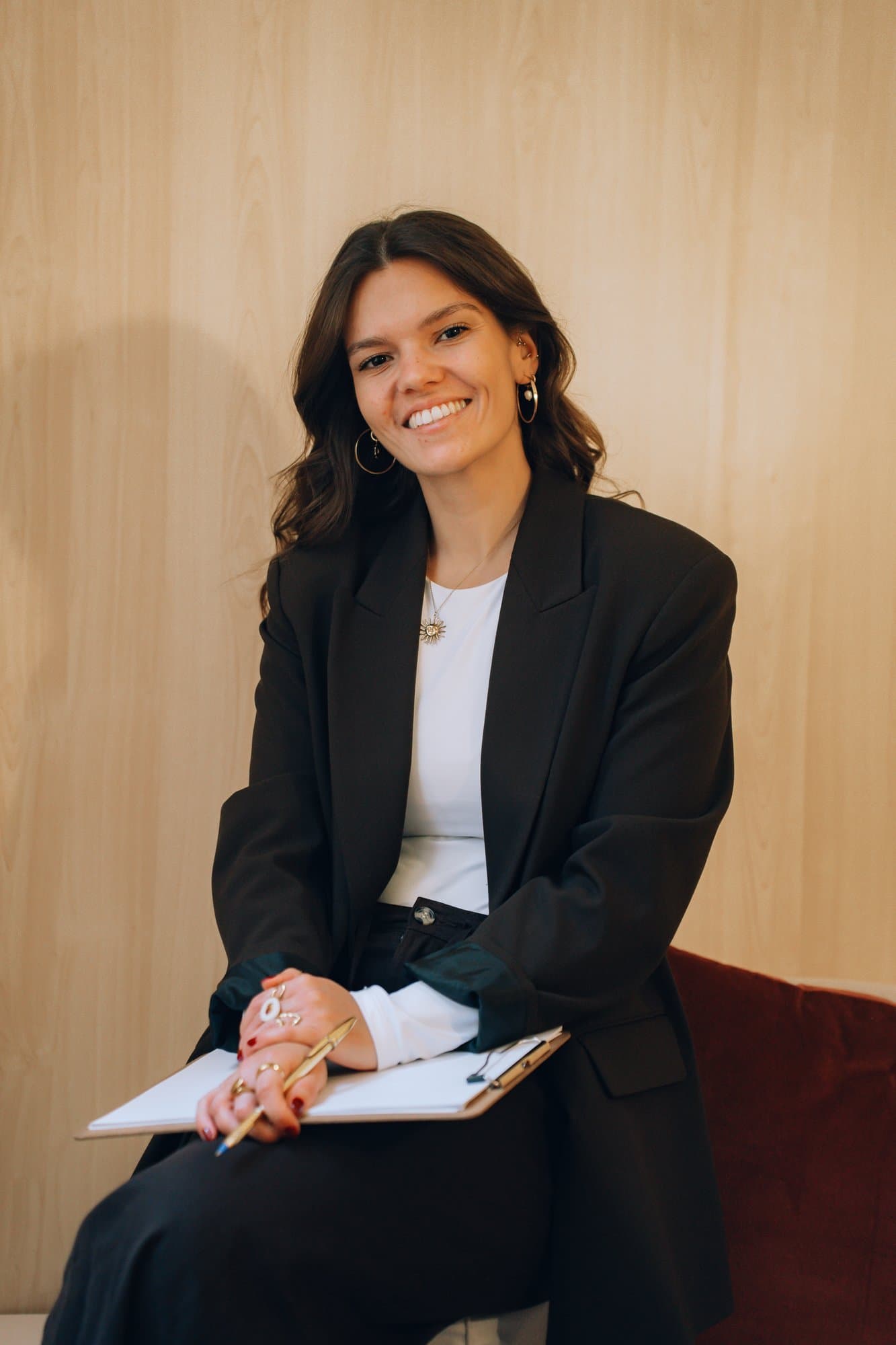 Aitana Barreda, psicóloga, sentada con clipboard y sonrisa natural